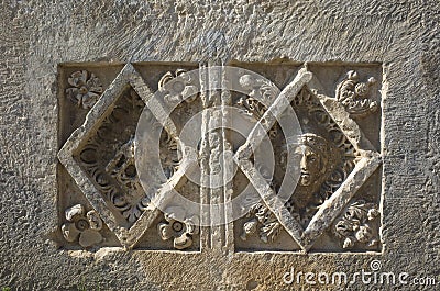 Ancient Lycian stone slab with human portrait and bird carved in stone in geometric form with floral decoration Stock Photo