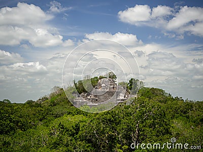 Ancient Mayan stone structure rising out of the jungle canopy at Stock Photo