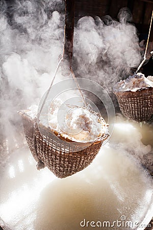 Ancient method of boiling brine into pure salt in Bo Kluea, Nan, Thailand. Beautiful smoke, sunlight shines down around ancient Stock Photo