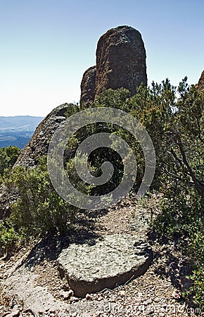 Ancient Millstone working below an outcrop of red rocks at La Col De la Pierre du Coucou Stock Photo