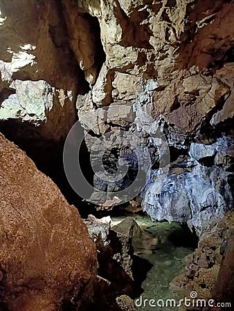 Ancient mountain cave with stalactites, stalagmites, long underground river in white and red stones with petroglyph Stock Photo