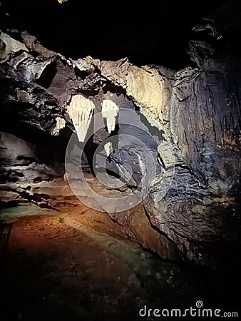 Ancient mountain cave with stalactites, stalagmites, long underground river in white and red stones with petroglyph Stock Photo
