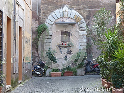 Ancient narrow street with a votive niche in the Trastevere distrct to Rome in Italy. Editorial Stock Photo