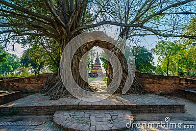 Ancient old pagoda in frame of door of ruined brick wall covered Editorial Stock Photo