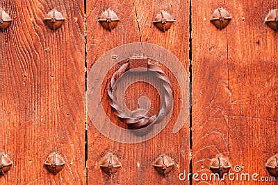 An ancient ornate iron knocker on an old wooden entrance door Stock Photo