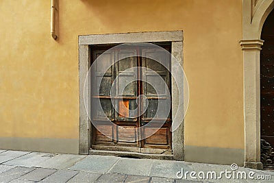 Ancient rustic woodden closed portal on yellow wall Stock Photo