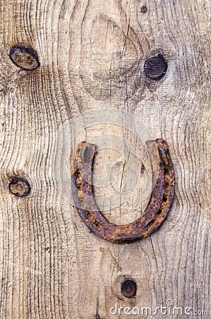 Ancient rusty horseshoe on old wooden plank background Stock Photo