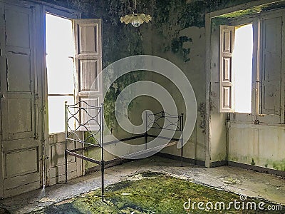 Ancient rusty iron bed in an abandoned and ruined room Stock Photo