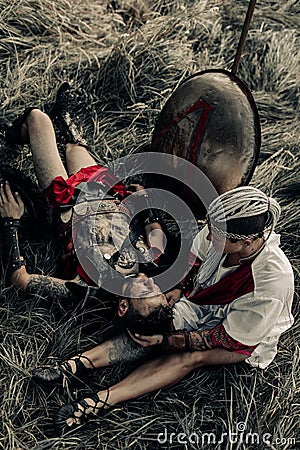 Ancient warrior in battle dress and his beloved woman rest among meadow Stock Photo