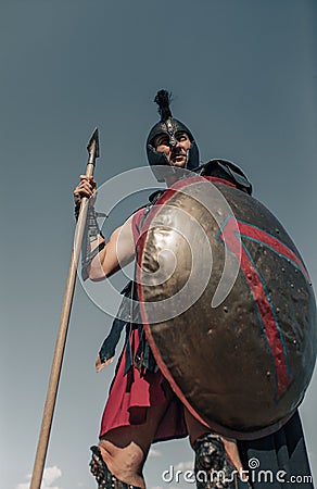 Ancient Spartan warrior in battle dress stands with shield and spear Stock Photo