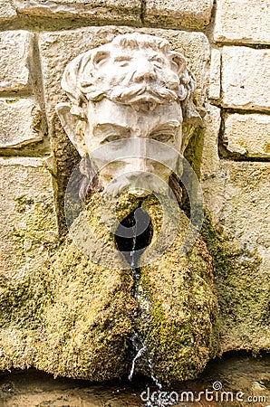 Ancient stone fountain. Fountain with head of man Stock Photo