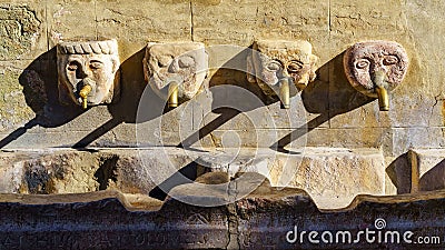 Ancient stone fountain with human faces and jets of water supplying fresh water, Andalucia, Spain. Stock Photo