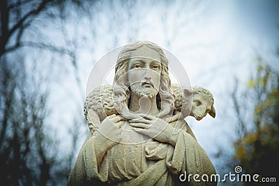 Ancient stone statue of Jesus Christ Good Shepherd with the lost sheep on his shoulders. Biblical history, religion, Christianity Stock Photo