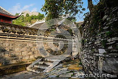 Ancient tile-roofed buildings behind wayside enclosure in morning Stock Photo