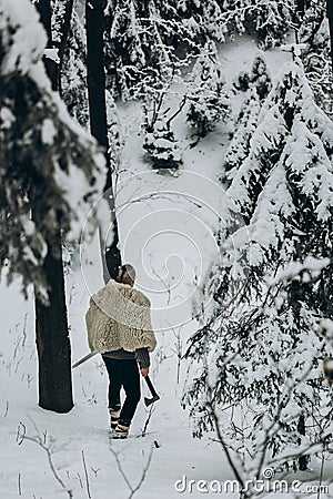 Ancient viking hunter walking in snow winter forest with steel a Stock Photo