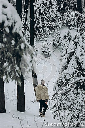 Ancient viking hunter walking in snow winter forest with steel a Stock Photo