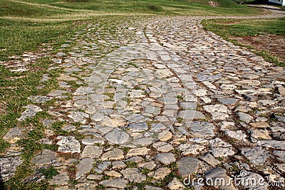 Ancient winding road paved with cobblestone . Stock Photo