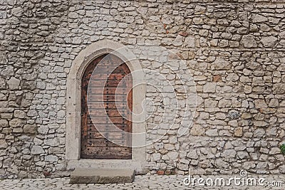 Ancient wooden arcade door with iron rivets at wall of old building Stock Photo