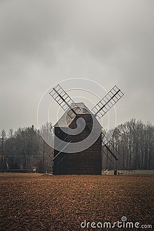 Ancient wooden mill standing alone in a field in gloomy foggy weather. Historical building for grinding corn, Opava, Czech Stock Photo