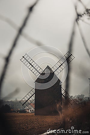 Ancient wooden mill standing alone in a field in gloomy foggy weather. Historical building for grinding corn, Opava, Czech Stock Photo