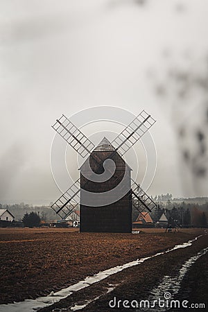 Ancient wooden mill standing alone in a field in gloomy foggy weather. Historical building for grinding corn, Opava, Czech Stock Photo