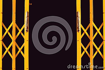 Ancient yellow expanded metal door on black background Stock Photo