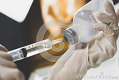 Anesthesiologist Doctors hand inject syringe into normal saline solution NSS bottle Stock Photo