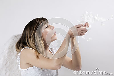 Angel blowing feathers off her hands Stock Photo