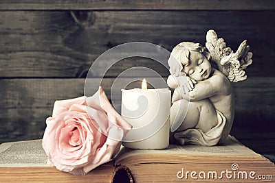 Angel, candle and pink rose on wooden background Stock Photo