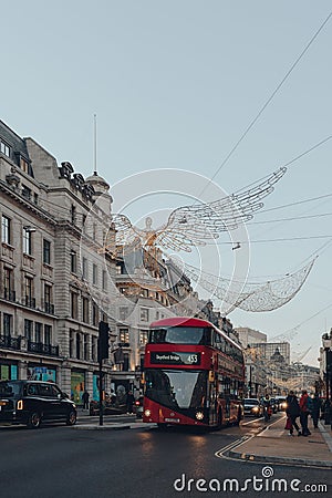 Angel Christmas lights on Regent Street, London, UK, red double decker bus on the road under Editorial Stock Photo