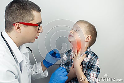 A pediatrician examines a boy who complains of a sore throat. Diagnosis of tracheal diseases. Angina, tonsillitis, pharyngitis, Stock Photo