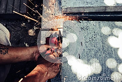 Angle grinder sparks angle grinder cutting steel. A worker cutting steel in concrete sheet with grinder. Stock Photo