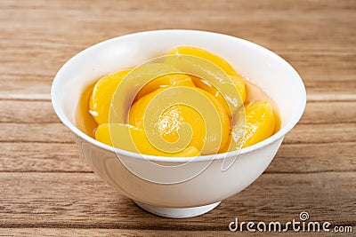 bowl of yellow peach syrup on wood background Stock Photo