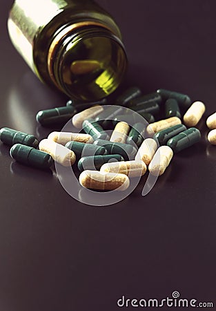 Angle view of pill bottle with green and white prescription medicine spilling across a black background a lot of space Stock Photo