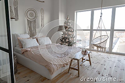 Angle view on spacious white bedroom with big windows decorated with Christmas New year tree and tea Stock Photo