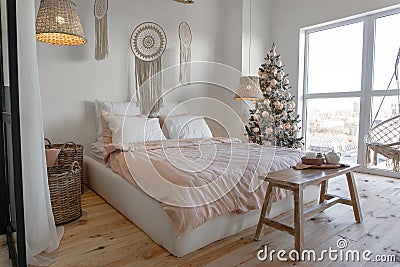 Angle view on spacious white bedroom decorated with Christmas New year tree and tea set standing on a bench Stock Photo