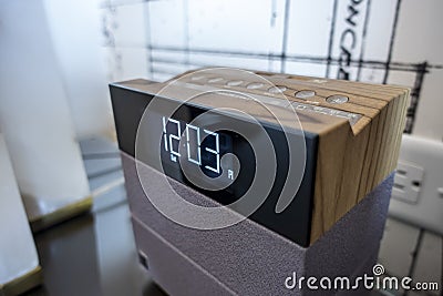 Angled view of a digital alarm clock on a bedside table in the bright, sunny afternoon Stock Photo