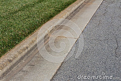 Angled view formed concrete curb, green grass and asphalt street Stock Photo