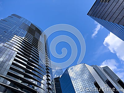 Angled view of large, window covered buildings against a blue, cloud filled sky Stock Photo