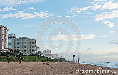 Anglers and Lifeguards on the Umhlanga Rocks beachfront with Millennium Pier and Lighthouse in the distance Editorial Stock Photo