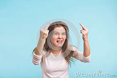 Angry aggressive woman with ferocious expression on blue background Stock Photo