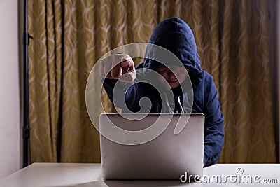 Angry Asian hacker pointing finger to camera while hacking network Stock Photo