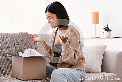 Angry asian woman unpacking wrong box, delivery mistake Stock Photo