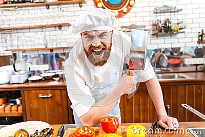 Angry bearded chef cook holding meat cleaver knife and shouting Stock Photo