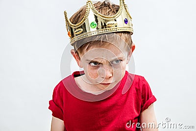 Angry beautiful spoiled kid wearing king crown facing unhappy parenthood Stock Photo