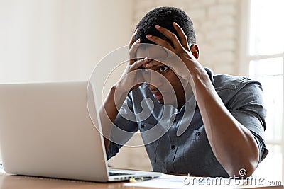 Angry biracial male employee annoyed with laptop operational problems Stock Photo