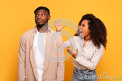 Angry black woman yelling at indifferent man on yellow background Stock Photo