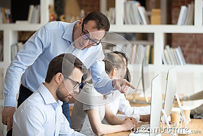 Angry boss criticizing scolding sad male employee for computer mistake Stock Photo