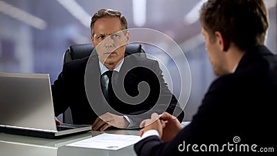 Angry boss looking at candidate, failed job interview, cv lying on table Stock Photo