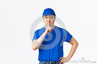 Angry and bossy serious-looking asian courier telling keep quiet, scolding employees misbehaviour at work. Delivery guy Stock Photo